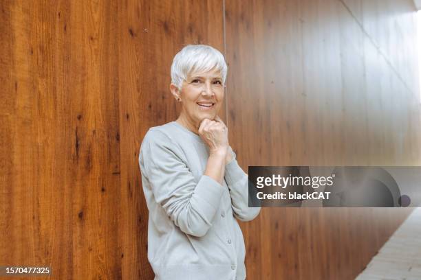 beautiful senior woman in front of the wooden background - people plain background stock pictures, royalty-free photos & images