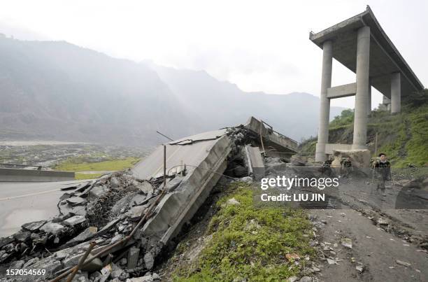 Rescuers walk past a collapsed bridge outside Yingxiu of Wenchuan county, after a quake with a magnitude of 7.8 rocked China on May 11, in the...