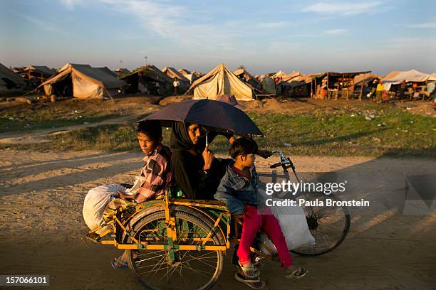 Rickshaw passes in front of a crowded IDP camp November 23, 2012 on the outskirts of Sittwe, Myanmar. An estimated 111,000 people were displaced by...