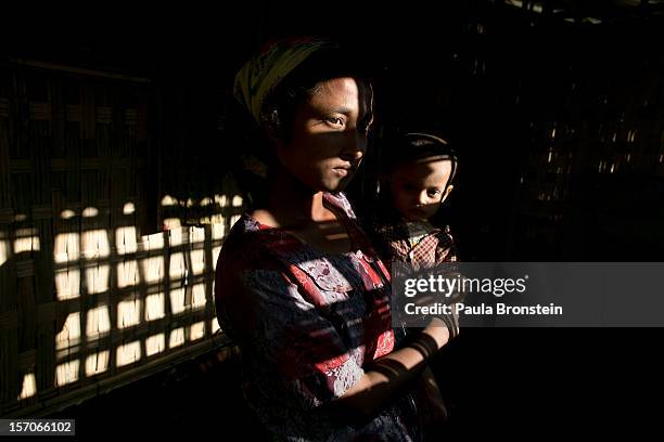 Amina Khatu holds her son Ahmed inside a thatched hut at a crowded IDP camp November 25, 2012 on the outskirts of Sittwe, Myanmar. An estimated...