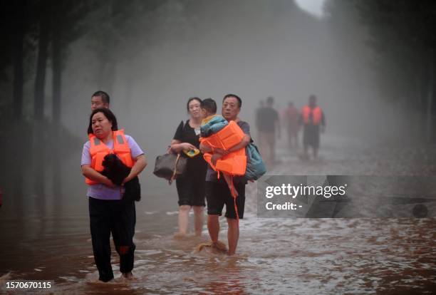 This photo taken on August 1, 2023 shows people evacuating from a flooded area after heavy rains in Zhuozhou, Baoding city, in China's northern Hebei...