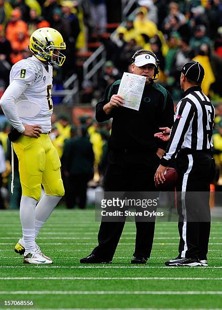 Head coach Chip Kelly of the Oregon Ducks speaks with the field judge as quarterback Marcus Mariota of the Oregon Ducks in the third quarter of the...