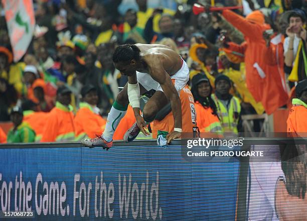 Ivory Coast's striker Didier Drogba jumps back over the barrier and onto the pitch after giving his shirt to a supporter after the Group G first...