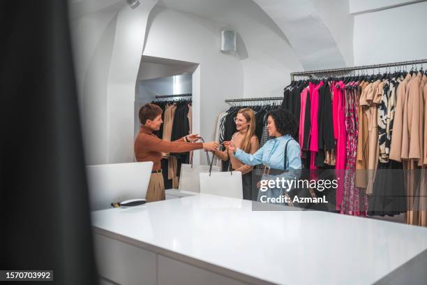 caucasian and latin american female friends shopping together - latin american and hispanic shopping bags stockfoto's en -beelden