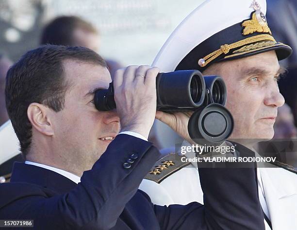 Russian President Dmitry Medvedev ext to the Commander-in-chief of the Navy Vladimir Vysotsky uses binoculars to watch a parade duriong a visit at...