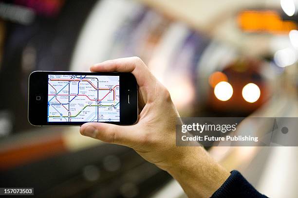 Man using an iPhone to view a map of the London Underground whilst waiting for a tube train, October 4, 2012.