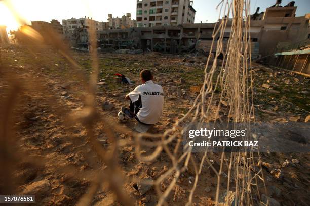 Palestinian runner and football player Bilal Abu Samaan sits in the rubble of the bombed Palestine Stadium in Gaza City on November 28, 2012. The...