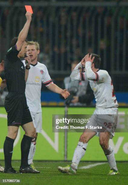 Referee Felix Zwayer shows the red card to Fin Bartels of St. Pauli while Patrick Funk of St. Pauli reacts during the Second Bundesliga match between...