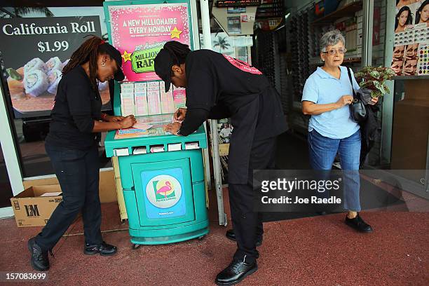 Monti Young and Twon Mackey fill out their Powerball numbers as they buy tickets at Circle News Stand on November 28, 2012 in Hollywood, Florida. The...