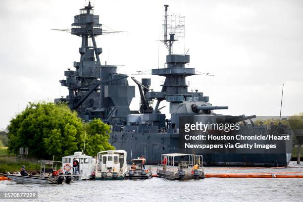 Cleanup workers dock their boats next to a containment buoy stretches across the water to protect the U.S.S. Texas as clean up continues along the...