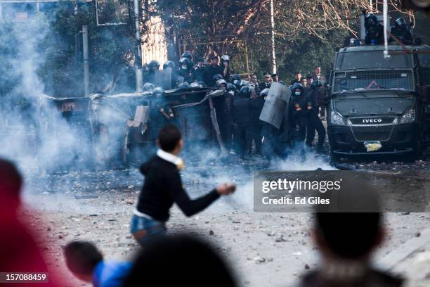 An Egyptian protester throws a rock toward riot police during demonstrations against Egyptian President Mohammed Mursi near Tahrir Square on November...