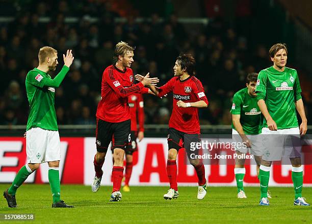 Simon Rolfes of Leverkusen celebrates with his team mate Hajime Hosogai after scoring his team's third goal during the Bundesliga match between...