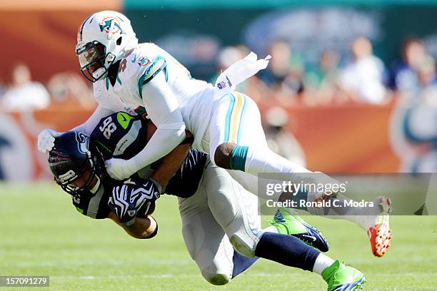 Tight end Zach Miller of the Seattle Seahawks is tackled by linebacker Kevin Burnett of the Miami Dolphins during a NFL game at Sun Life Stadium on...
