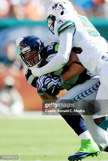 Tight end Zach Miller of the Seattle Seahawks is tackled by linebacker Kevin Burnett of the Miami Dolphins during a NFL game at Sun Life Stadium on...