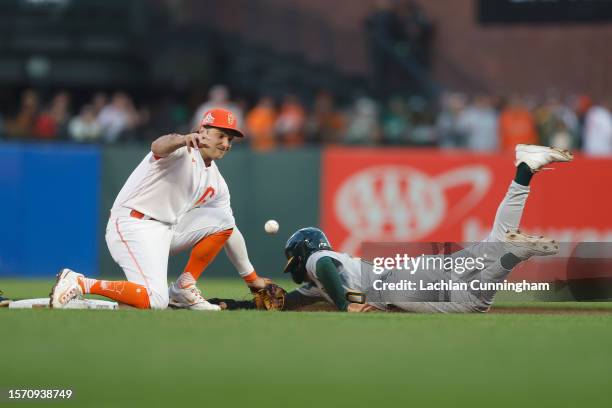 Zack Gelof of the Oakland Athletics safely steals second base as fielder Casey Schmitt of the San Francisco Giants is unable to gather the ball in...