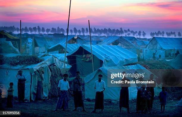 Rohingya refugees stand at a crowded internally displaced persons camp after sunset November 24, 2012 on the outskirts of Sittwe, Myanmar. An...