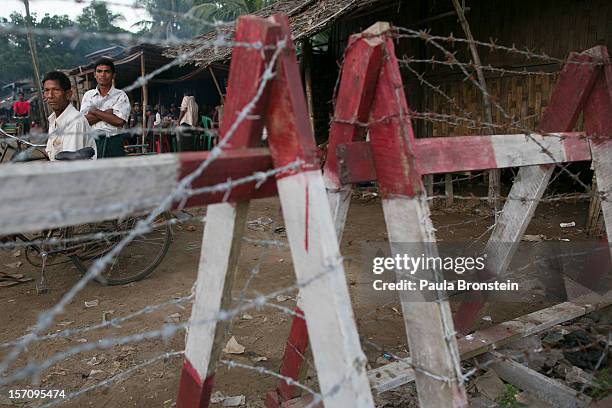 Rohingya man looks out from a barbed wire fence used as a barrier to restrict travel November 25, 2012 on the outskirts of Sittwe, Myanmar. An...