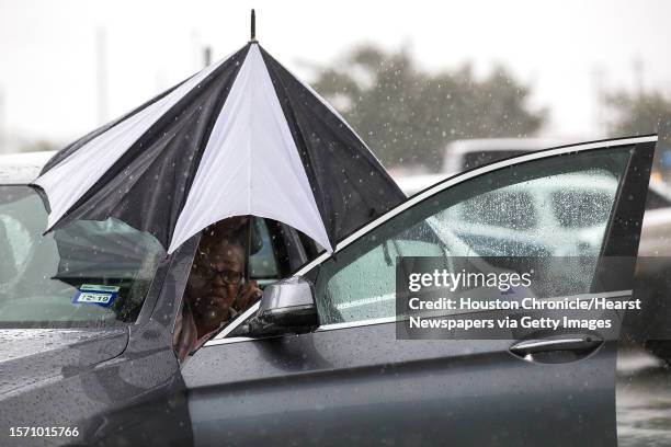 Woman closes her umbrella after getting into her car during a rain storm stemming from rain bands spawned by Tropical Storm Imelda near I-45 and...