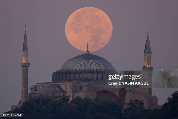 The Sturgeon super moon rises over the Ayasofya-i Kebir Camii or Hagia Sophia Grand Mosque in Istanbul on August 2, 2023.