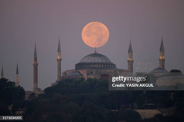 The Sturgeon super moon rises over the Ayasofya-i Kebir Camii or Hagia Sophia Grand Mosque in Istanbul on August 2, 2023.