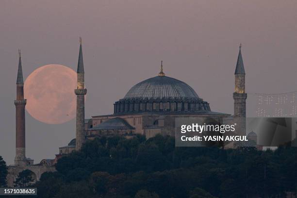 The Sturgeon super moon rises over the Blue Mosque and Ayasofya-i Kebir Camii or Hagia Sophia Grand Mosque in Istanbul on August 2, 2023.