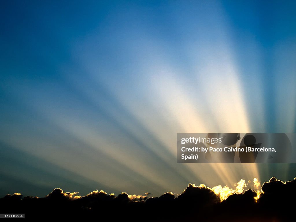 Rayos de sol en cielo azul sobre nubes