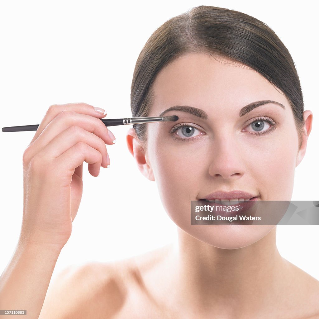 Portrait of woman applying eye make up.