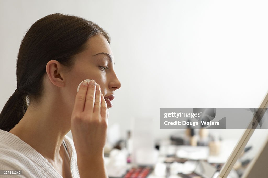 Woman removing make up with products in background