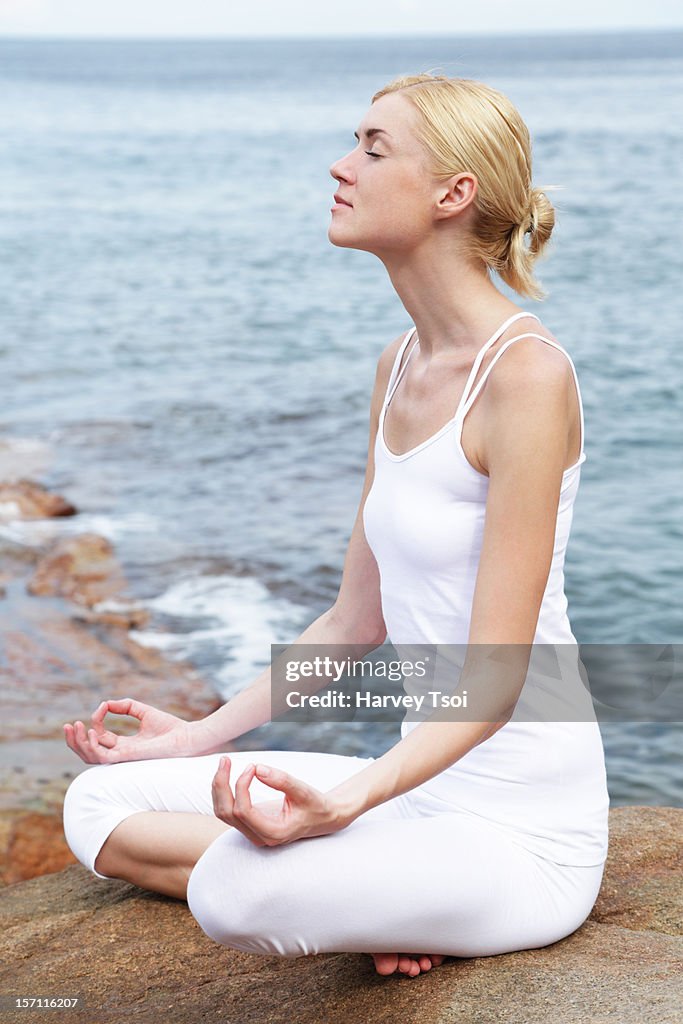 Young woman meditating outdoors by the sea