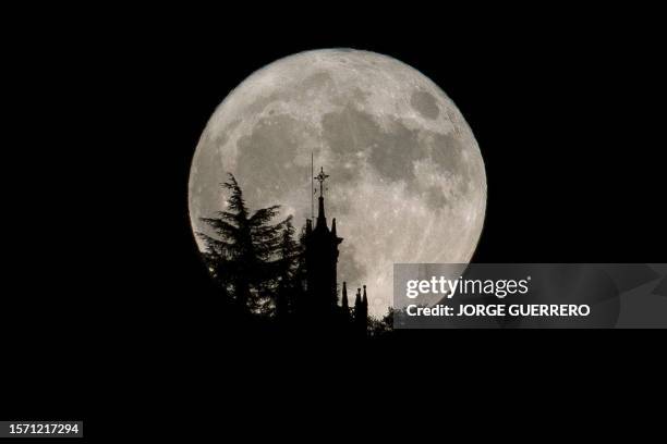 This picture taken late on August 1, 2023 shows the second supermoon of 2023, also known as the Sturgeon Moon, behind Santa Maria la Mayor church in...