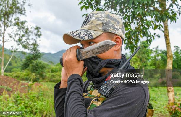 Kuki tribesman talks on the phone while on duty outside his bunker on the boundary line that divides the area into two ethnic zones, in...