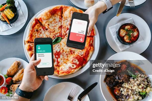 table top view of two people splitting bill, sending / receiving payment of the meal through digital wallet device on smartphone while dining together in restaurant. money transfer. smart banking with technology - wire transfer stock pictures, royalty-free photos & images