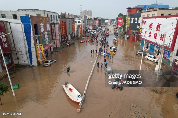 This aerial view shows rescue teams working in a flooded village after heavy rains in Zhuozhou, Baoding city, in northern China's Hebei province on...