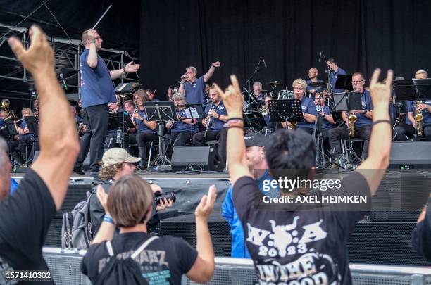 Festival-goer shows the sign of the horns hand gesture as the Wacken Firefighters' brass band opens the Wacken Open Air music festival on August 2,...