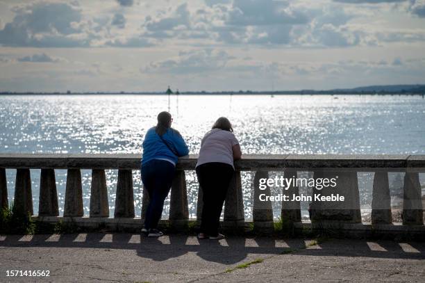 Two women look out over the Thames estuary on July 25, 2023 in Southend on Sea, England.