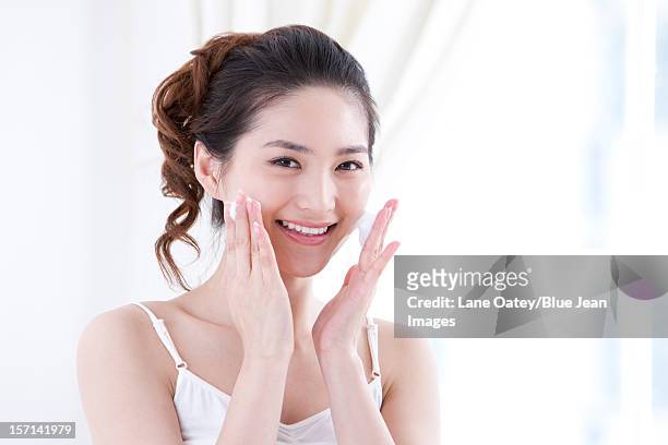 young woman using facial cleanser to wash face - frau gesicht schaum stock-fotos und bilder