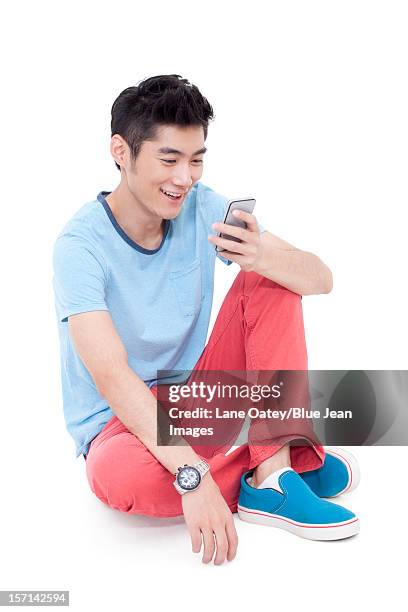 happy young man and a mobile phone - sitting and using smartphone studio stock pictures, royalty-free photos & images