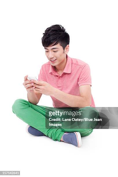 happy young man and mobile phone - sitting and using smartphone studio stock-fotos und bilder