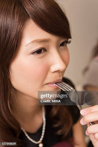 young woman holding fork in her mouth - carrying in mouth stock pictures, royalty-free photos & images