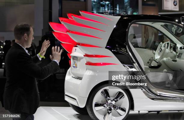 Reporter gestures next to a Daimler AG Smart car during the LA Auto Show in Los Angeles, California, U.S., on Wednesday, Nov. 28, 2012. The LA Auto...