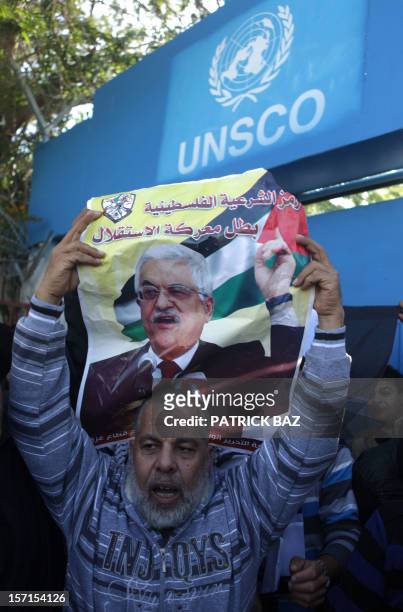 Supporter of Palestinian leader Mahmud Abbas raises his picture during a rally in front of the United Nations offices in Gaza City on November 29,...