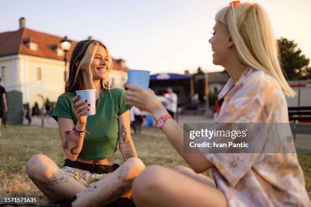 happy women talking while enjoying in drinks at music festival. - music festival grass stock pictures, royalty-free photos & images