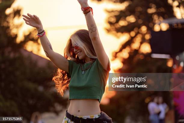 junge glückliche frau, die spaß beim tanzen auf einem musikfestival bei sonnenuntergang hat. - pop music stock-fotos und bilder