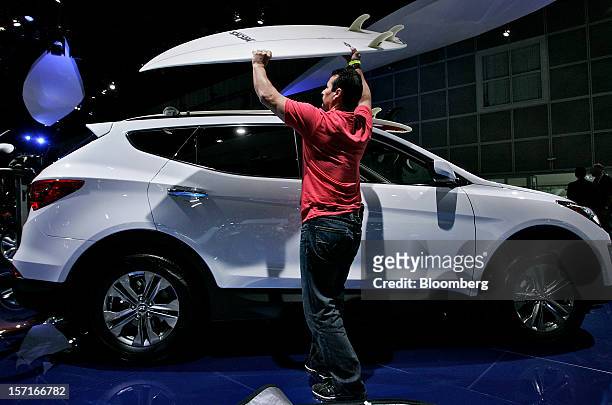 Man places a surfboard on top of a Hyundai Motor Co. Santa Fe vehicle during the LA Auto Show in Los Angeles, California, U.S., on Thursday, Nov. 29,...