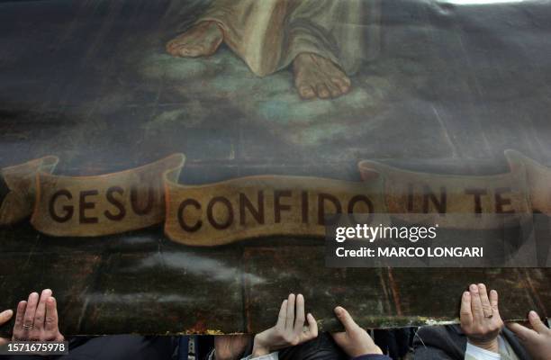 Faithfuls hold a painting representing the Christ and bearing an inscription reading "Jesus I have trust in you" during an open air mass in memory of...