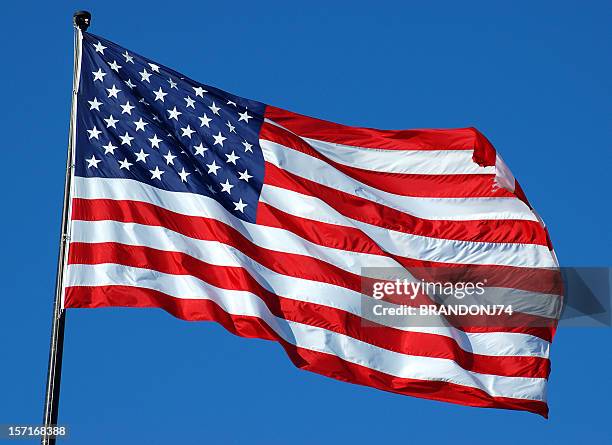 american flag flying high on top of flag pole on a clear day - pole stock pictures, royalty-free photos & images