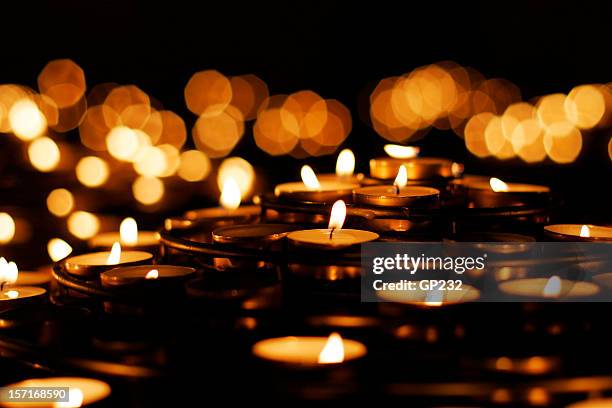 a collection of lit prayer candles against a dark backdrop - candlelight stock pictures, royalty-free photos & images