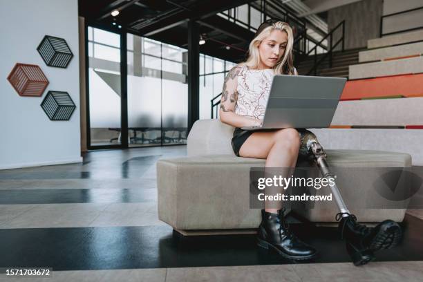 woman with prosthetic leg working on laptop - artificial limb stock pictures, royalty-free photos & images