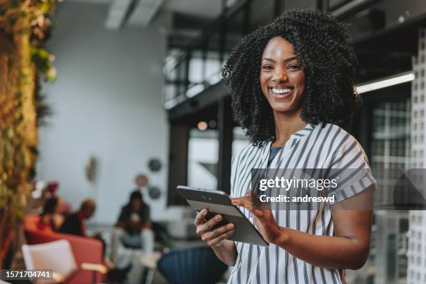 business woman holding digital tablet smiling - black woman smiling tablet stockfoto's en -beelden