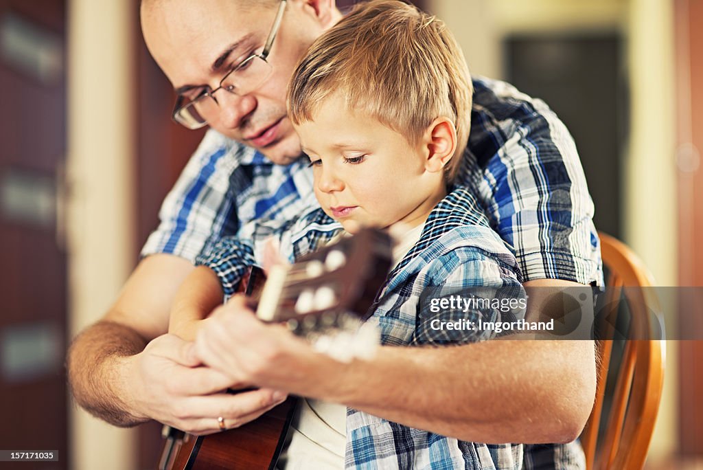 Father teaching son about playing guitar